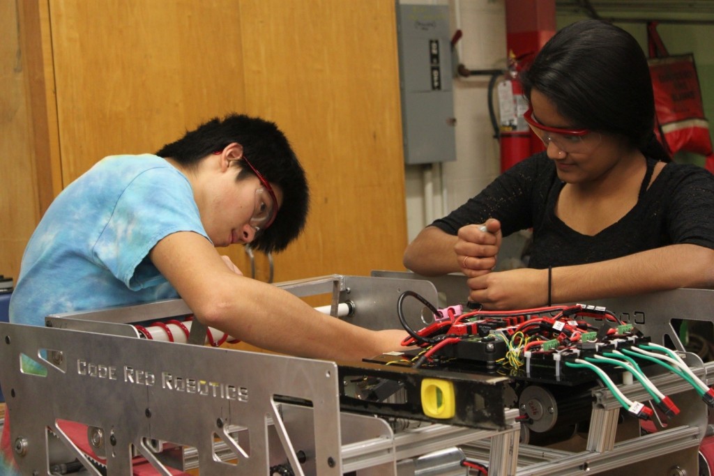 Seniors Pooja Reddy and Kenzo Uchigasaki work together on the 2016 robot frame, even as electronic components are being installed at the front. The team's electronics subteam designs and assembles all of the robot's electronics. Other subteams handle programming, media, CAD, and machining.